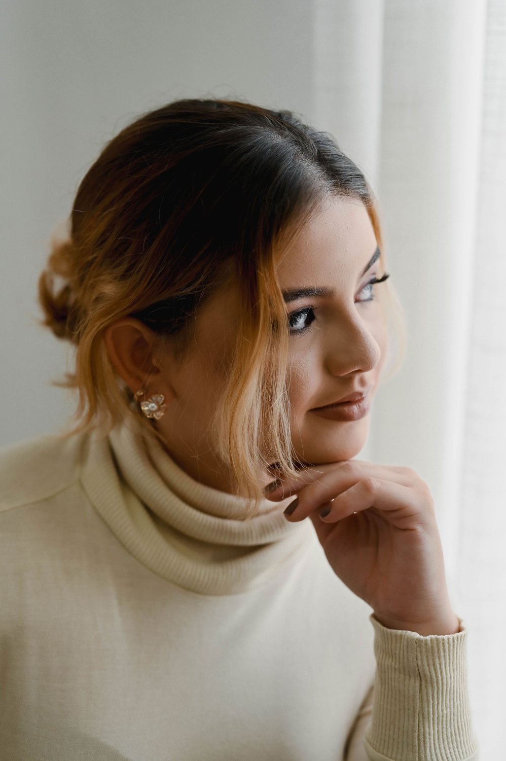 Nicole Louzada de perfil, com a mão no queixo